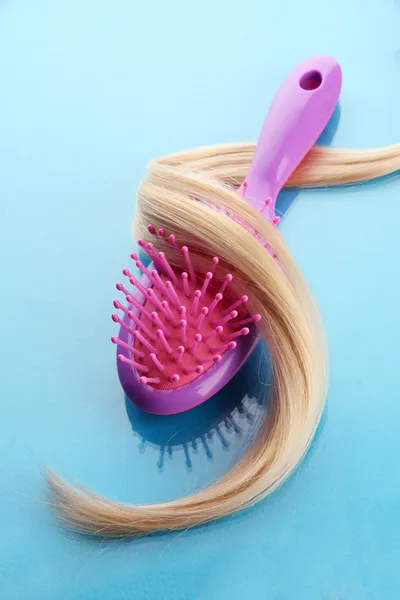 Comb brush with hair, on blue background — Stock Photo, Image