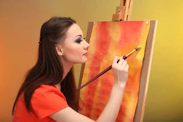 Beautiful young woman painter at work, on bright color background — Stock Photo, Image