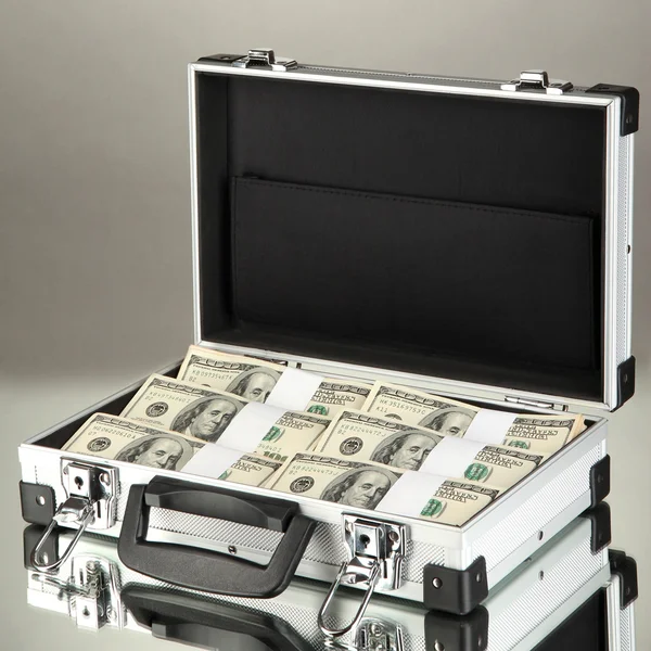 Koffer mit 100-Dollar-Scheinen auf grauem Hintergrund — Stockfoto