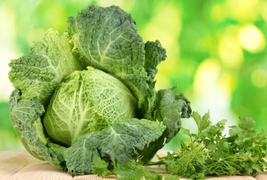 Fresh savoy cabbage on wooden table on natural background