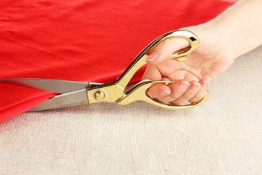 bej kumaş arka plan üzerinde kırmızı kumaş kesmek bir terzi