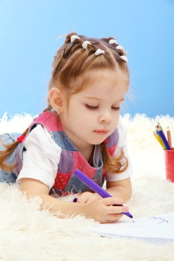 mavi zemin üzerine çok renkli kalemler ile oynarken sevimli küçük kız