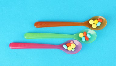 plastik kaşık ile mavi arka plan üzerinde renkli hapları