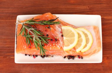 bitkiler ve ahşap zemin üzerinde plaka üzerinde limon dilimleri ile taze somon fileto