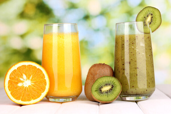 fresh fruit juices on wooden table, on green background