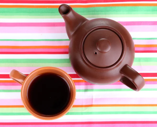 Top view of cup of tea and teapot on colorful tablecloths — Stock Photo, Image