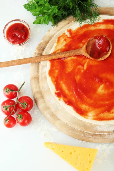 Pizza dough with tomato sauce on wooden board isolated on white — Stock Photo, Image