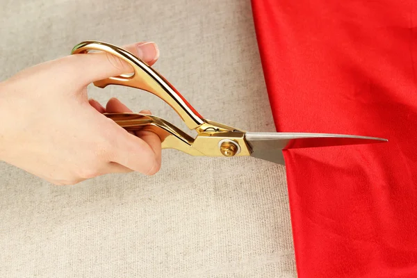 Costurera corte tela roja sobre fondo de tela beige —  Fotos de Stock