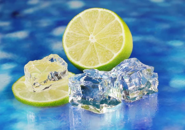 Ice cubes with lime on blue background — Stock Photo, Image