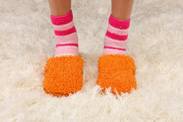 Female legs in color slippers, on carpet background — Stock Photo, Image