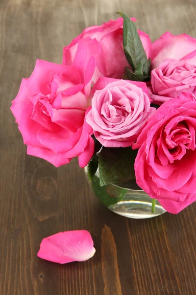 Vacker rosa rosor i vas på träbord närbild — Stockfoto
