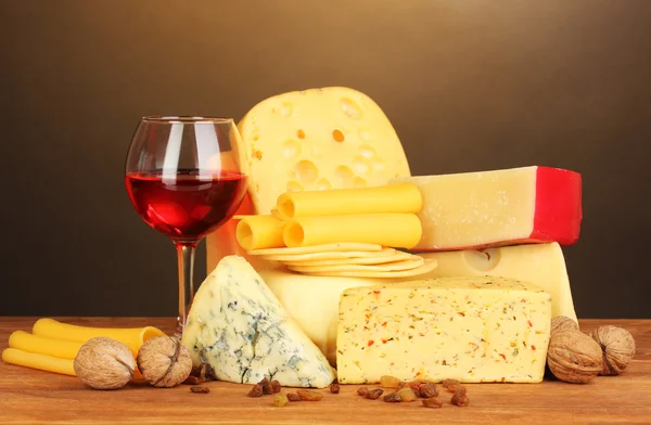 Varios tipos de queso sobre mesa de madera sobre fondo marrón — Foto de Stock
