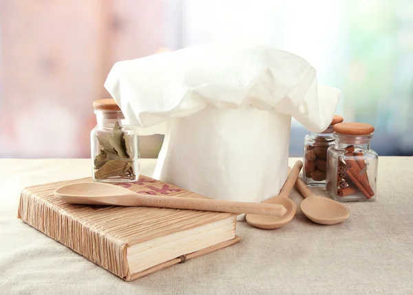 Chapéu de chef com colheres na mesa na cozinha — Fotografia de Stock