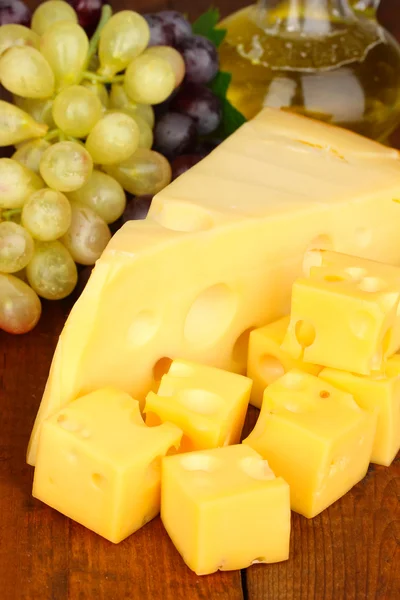 Formaggio tagliato con uva sul tavolo di legno — Foto Stock