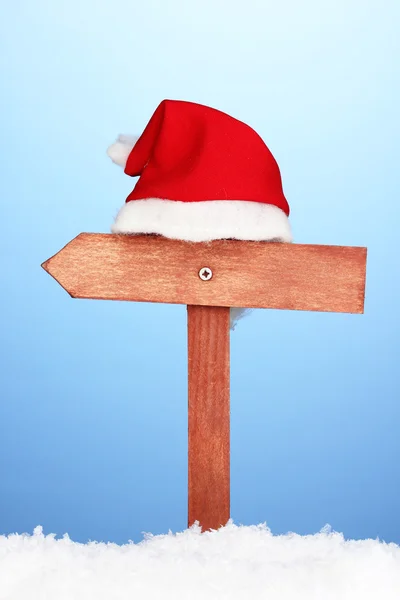 Hölzernes Verkehrsschild mit Weihnachtsmütze auf blauem Hintergrund — Stockfoto