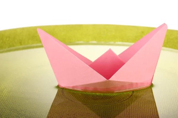 Color paper ship in water on green plate, close-up — Stock Photo, Image