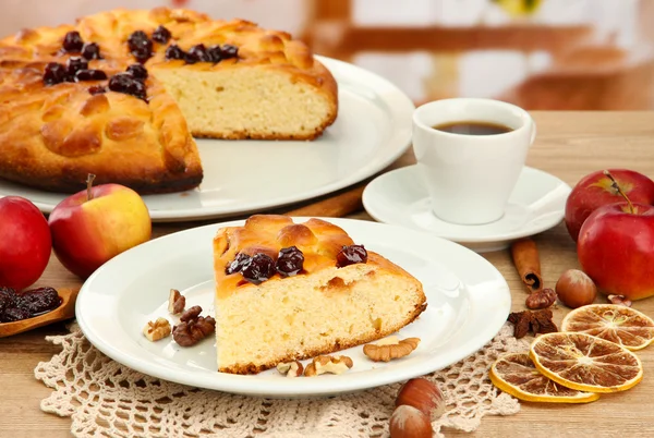 Slice of tasty homemade pie with jam and apples and cup of coffee, on wooden table — Stock Photo, Image