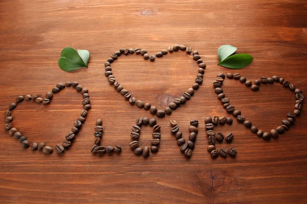 Koffie bonen met bladeren op houten achtergrond — Stockfoto