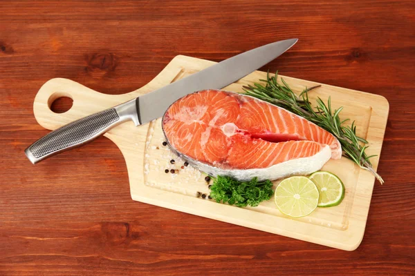 Fresh salmon steak on cutting board, on wooden background — Stock Photo, Image