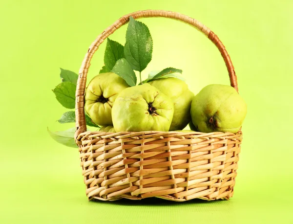 Sweet quinces with leaves in basket, on green background — Stock Photo, Image