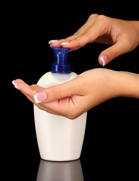 Frau drückt Lotion auf ihre Hand, Nahaufnahme auf schwarzem Hintergrund — Stockfoto