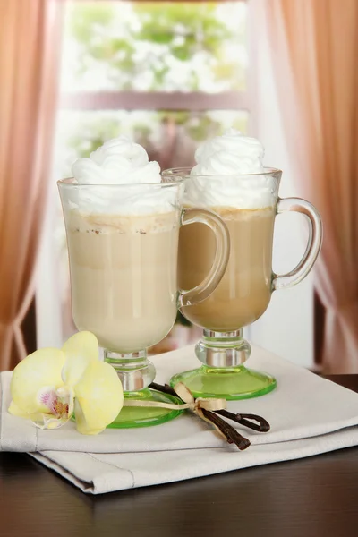 Café con leche fragante en vasos tazas con vainas de vainilla, en la mesa en la cafetería — Foto de Stock