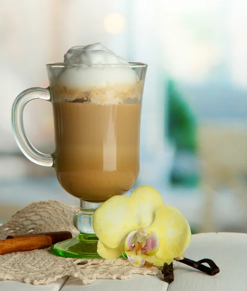 Café con leche fragante en taza de vidrio con especias, sobre mesa de madera —  Fotos de Stock