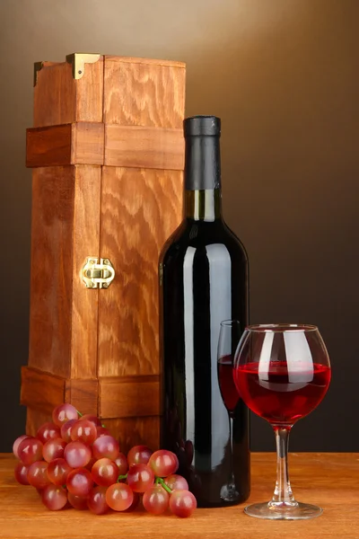 Caja de madera con botella de vino sobre mesa de madera sobre fondo marrón — Foto de Stock