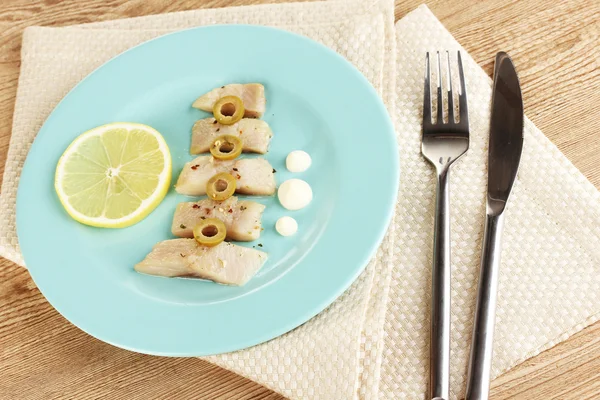 Dish of herring and lemon on plate on wooden table close-up — Stock Photo, Image