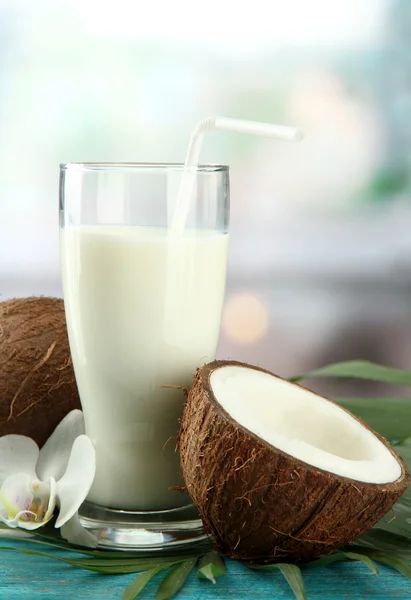 Kokosnöt med glas mjölk, på blå träbord — Stockfoto