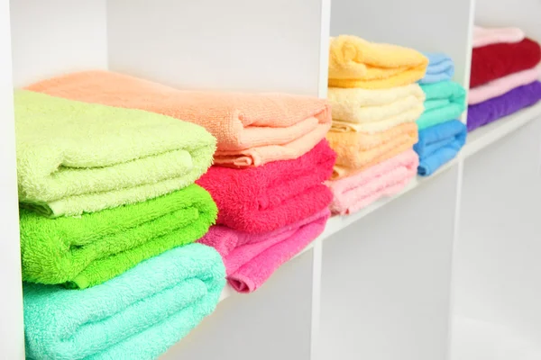 Serviettes colorées sur les étagères dans la salle de bain — Photo