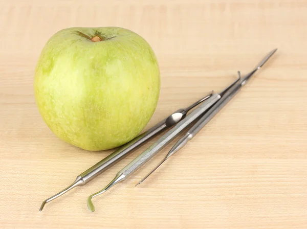 Green apple and dental tools on wooden background — Zdjęcie stockowe