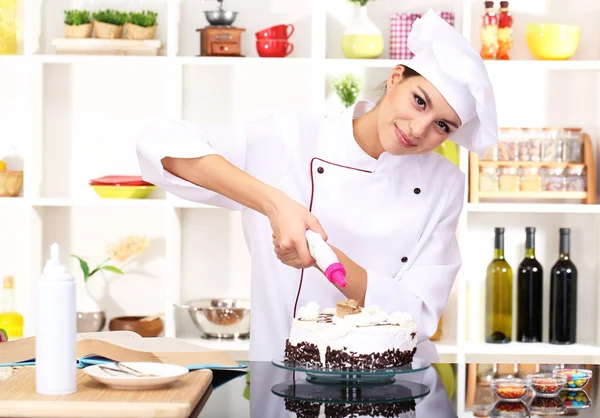 Joven cocinera cocinando pastel en la cocina — Foto de Stock