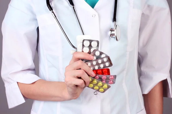 Primo piano della mano medico femminile che tiene pillole, su sfondo a colori — Foto Stock