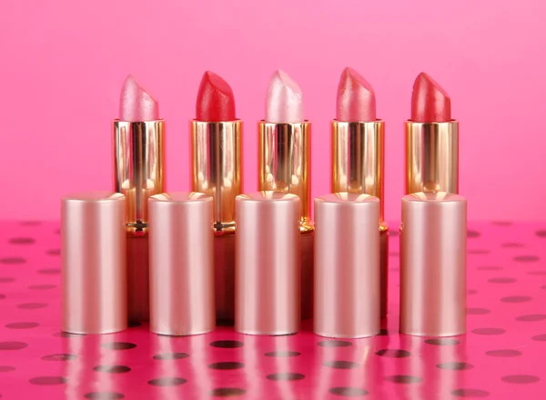 Lippenstiften op tafel op roze achtergrond — Stockfoto