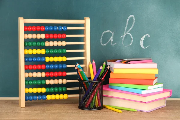 Toy abacus, books and pencils on table, on school desk background — Stock Photo, Image