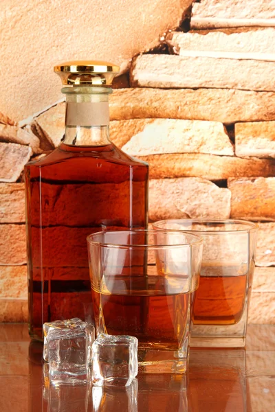 Bouteille et verres de whisky et de glace sur fond de mur de briques — Photo