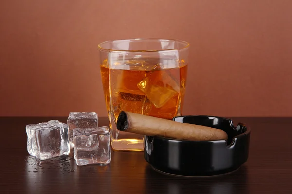 Vaso de whisky y cigarro sobre fondo marrón — Foto de Stock