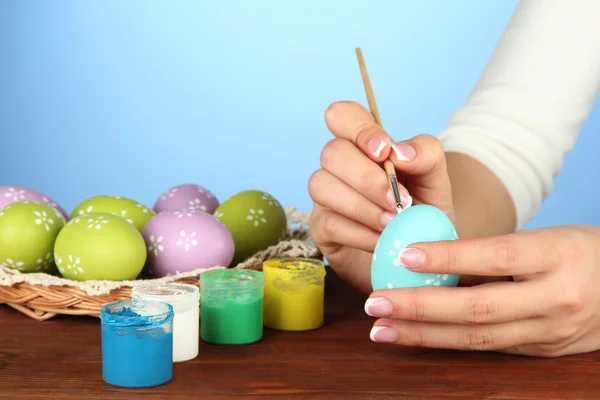 Νεαρή γυναίκα ζωγραφική Πασχαλινά αυγά, σε φόντο χρώμα — Φωτογραφία Αρχείου