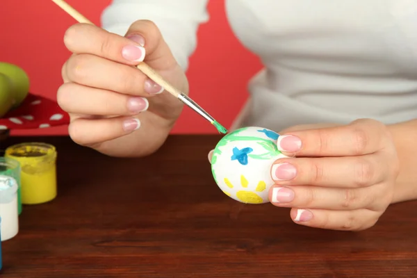 Mujer joven pintando huevos de Pascua, sobre fondo de color — Foto de Stock