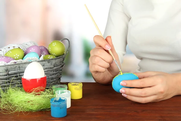 Mujer joven pintando huevos de Pascua, sobre fondo brillante —  Fotos de Stock