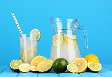 narenciye limonata sürahi ve bardak narenciye çevresinde mavi zemin üzerine ahşap tablo