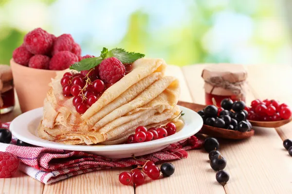 Pancake dengan buah beri, selai dan madu di atas meja kayu dengan latar belakang hijau — Stok Foto