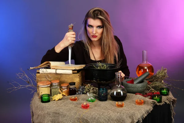 Halloween witch preparing poison soup in her cauldron on color background — Stok fotoğraf