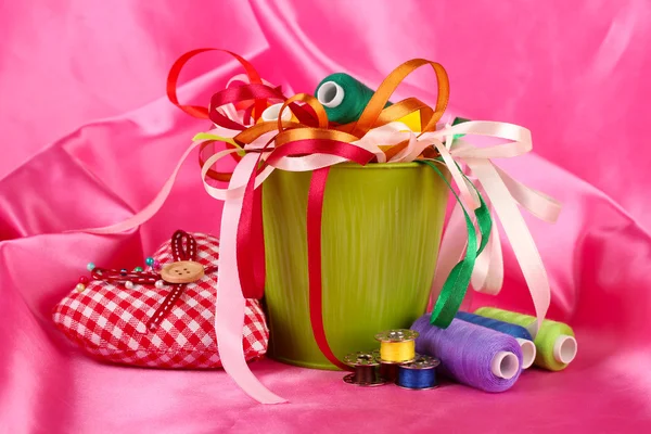 Cubo de color con cintas multicolor e hilo sobre fondo de tela rosa —  Fotos de Stock
