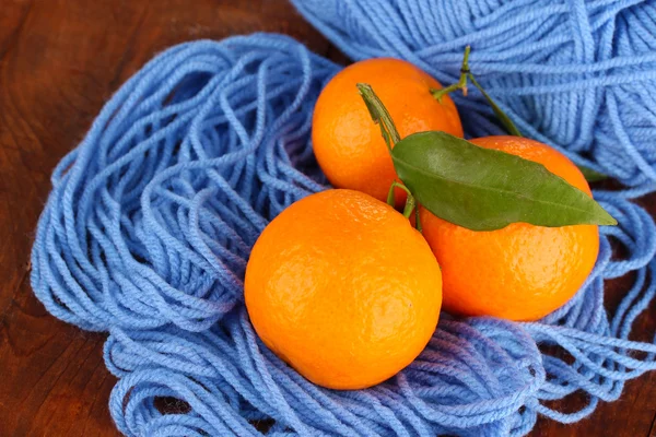 Sweet tangerines with leaves, on blue yarn background — Stock Photo, Image