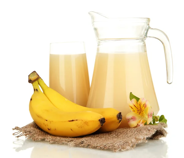 Verre plein et cruche de jus de banane et bananes isolées sur blanc — Photo