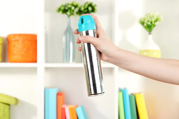 Sprayed air freshener in hand on white shelves background — Stock Photo, Image