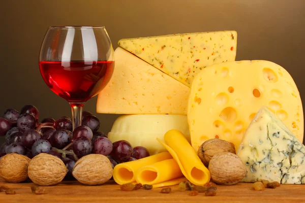 Various types of cheese on wooden table on brown background — Stock Photo, Image