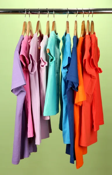 Variedade de camisas casuais em cabides de madeira, no fundo verde — Fotografia de Stock